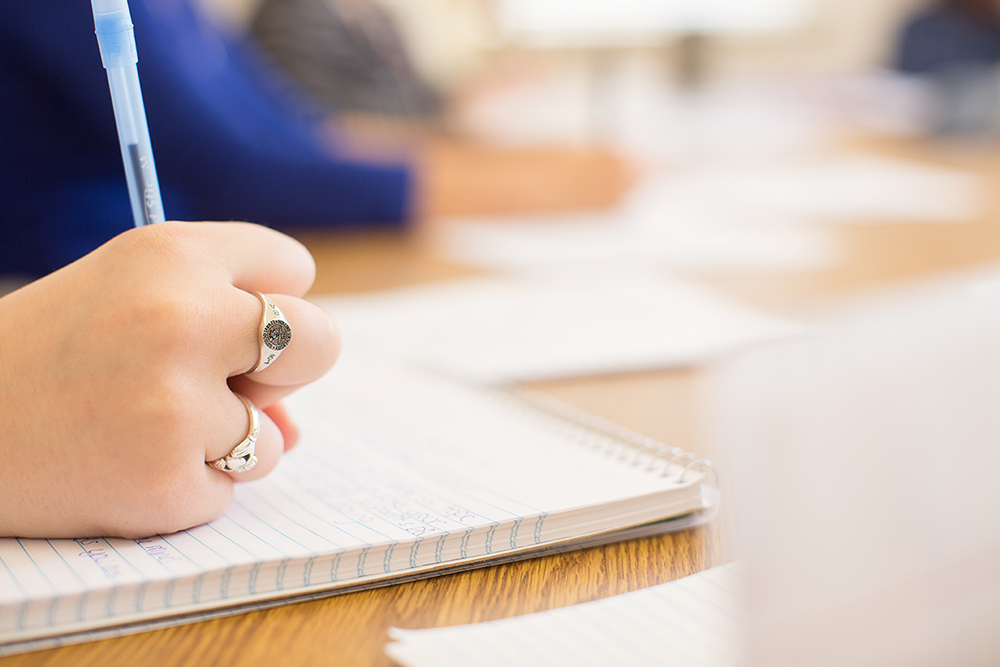 Student writing at desk